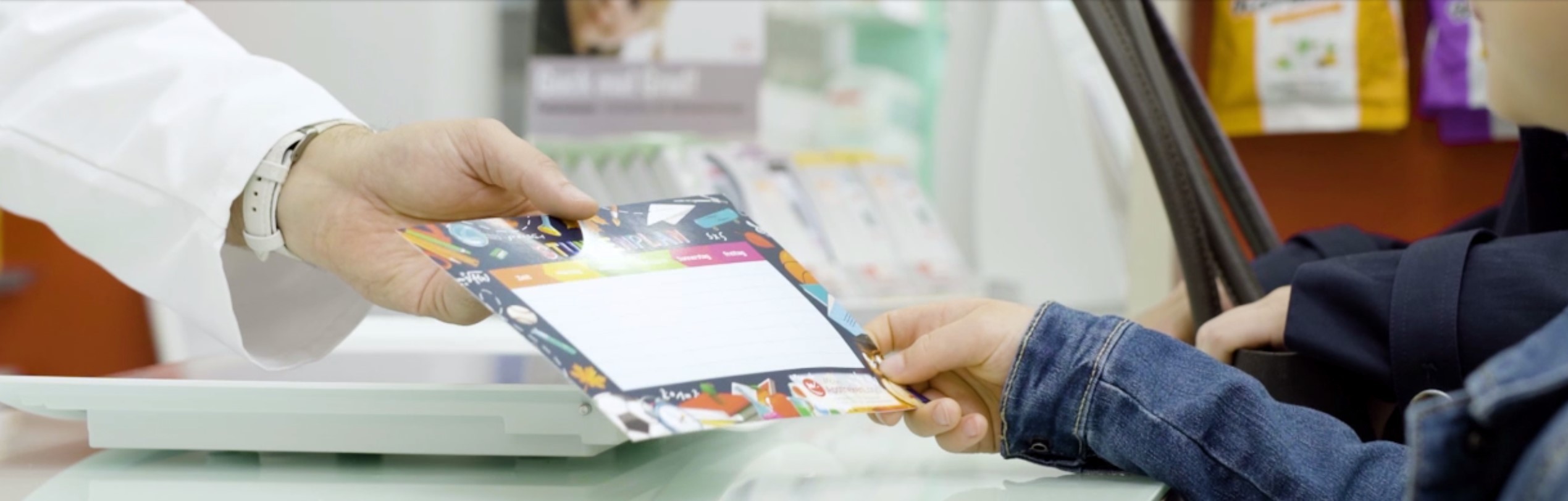 Übergabe eines Kalenders Eine Hand überreicht einer anderen Hand einen Kalender zum Eintragen