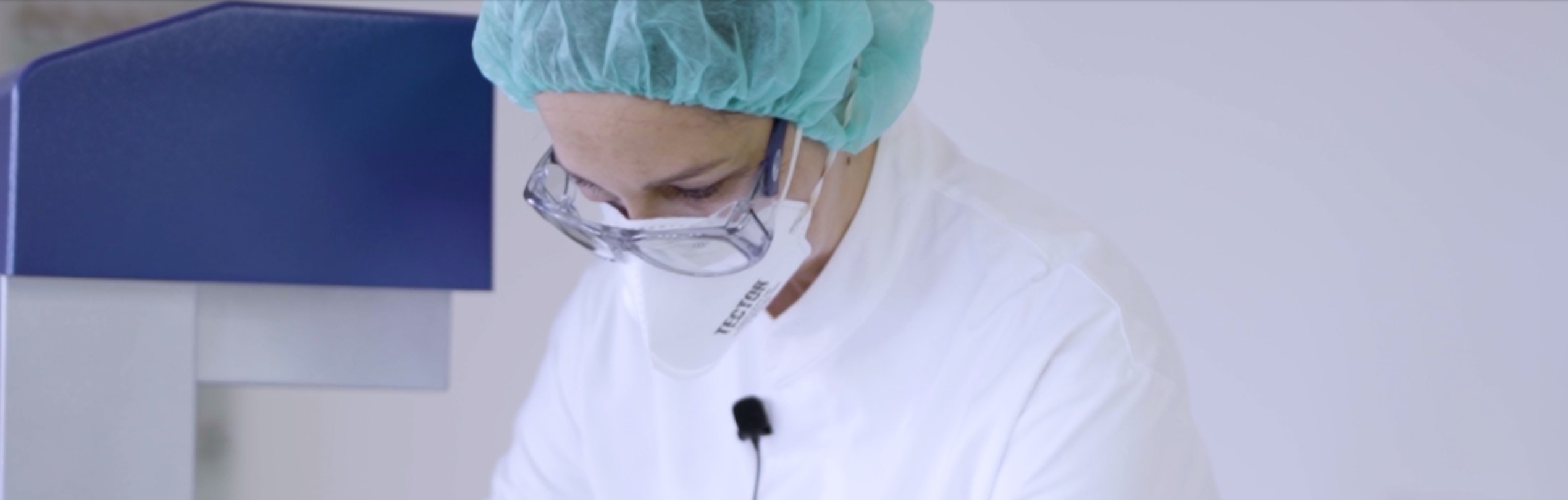 Apothekerin mit weißem Kittel, blauer Haube und Schutzbrille