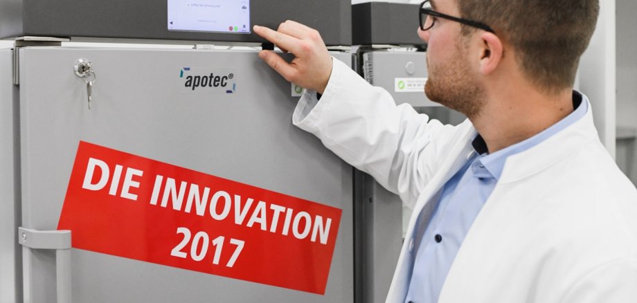 apotec Kühlschrank. Ein Apotheker schaut sich die Kühlregelung eines apotec Kühlschrankes an. Auf dem Kühlschrank steht die Innovation 2017.