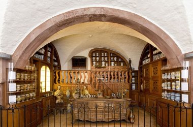 Das deutsche Apothekenmuseum in Heidelberg ist zu sehen. Apothekenbedarf in holzfarbenden Regalen sind dort platziert.