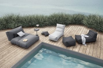 Graue und Beige , wasserabweisende Liegen um den Pool aufgestellt sind zu sehen.  Hinter den Liegen befindet sich in der Aussicht direkt das Meer.
